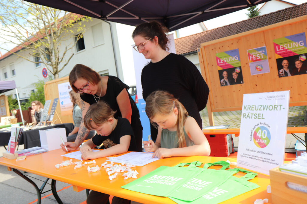 Kinder lösen ein Kreuzworträtsel am Stand der Stadtbibliothek Puchheim