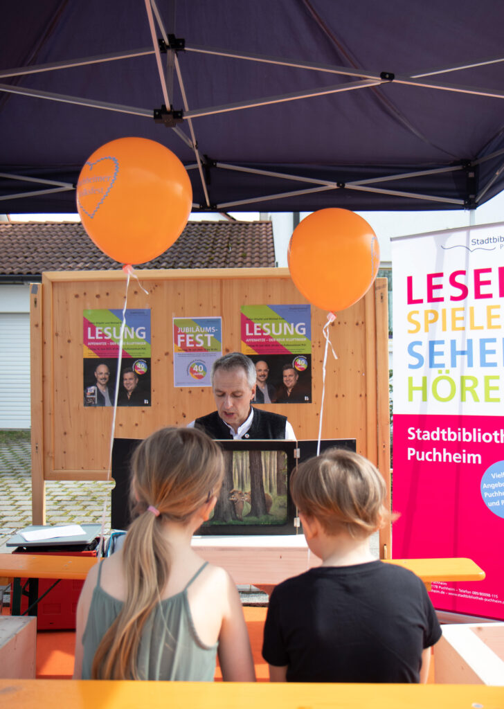 Der Bürgermeister liest Kindern vor beim Stand der Stadtbibliothek Puchheim