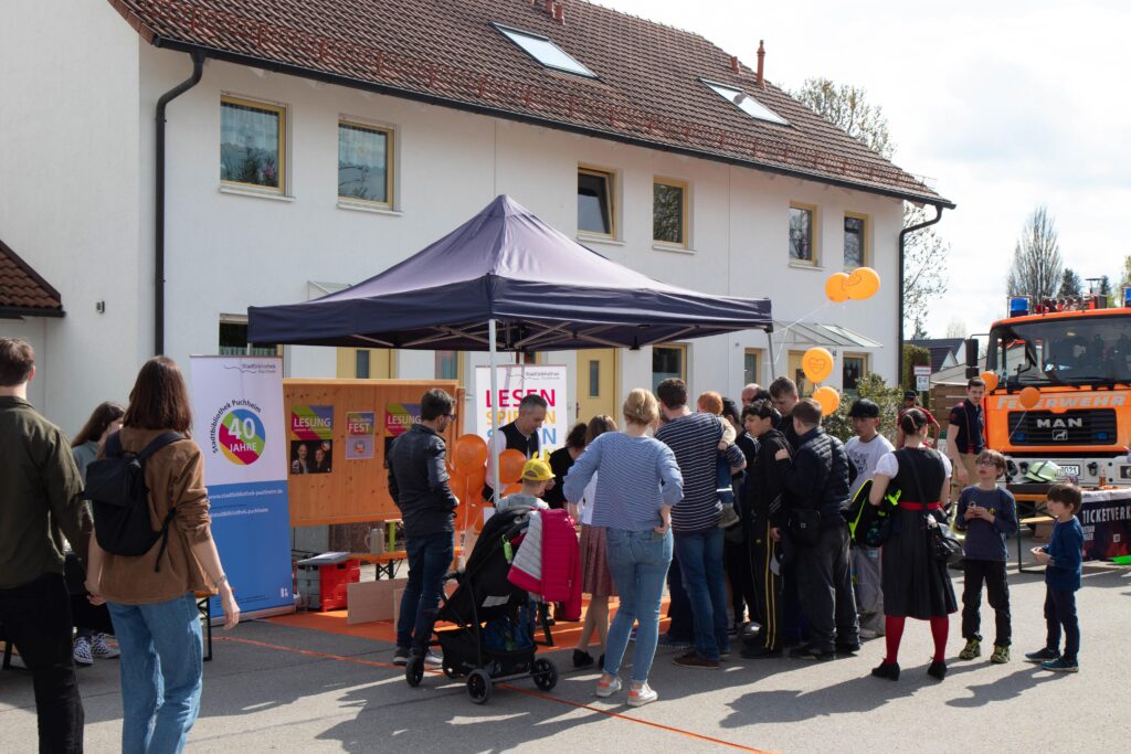 Infostand der Stadtbibliothek Puchheim beim Tag der Stadt, umgeben von Besuchern