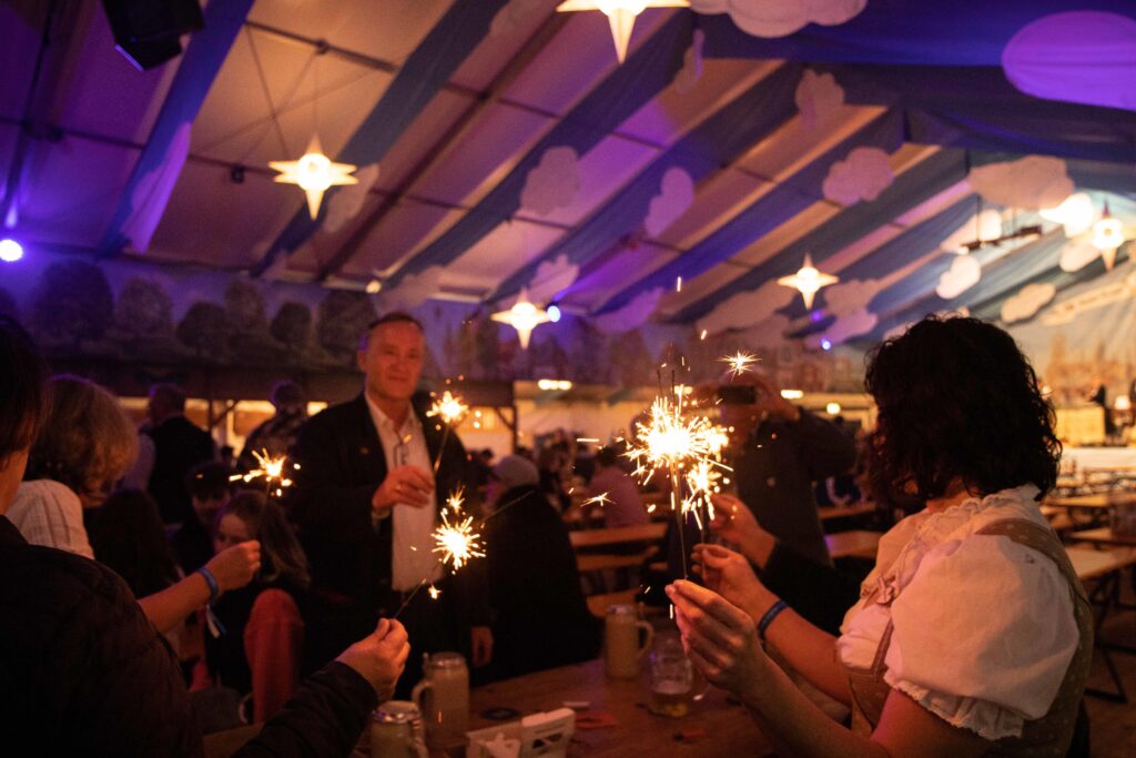 Menschen im Festzelt mit brennenden Wunderkerzen beim Ausklang des Volksfestes 2023