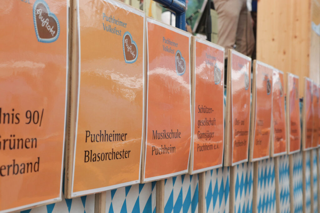 Die Vereinstafferl der Festzugsteilnehmer:innen platziert bei der Bühne
