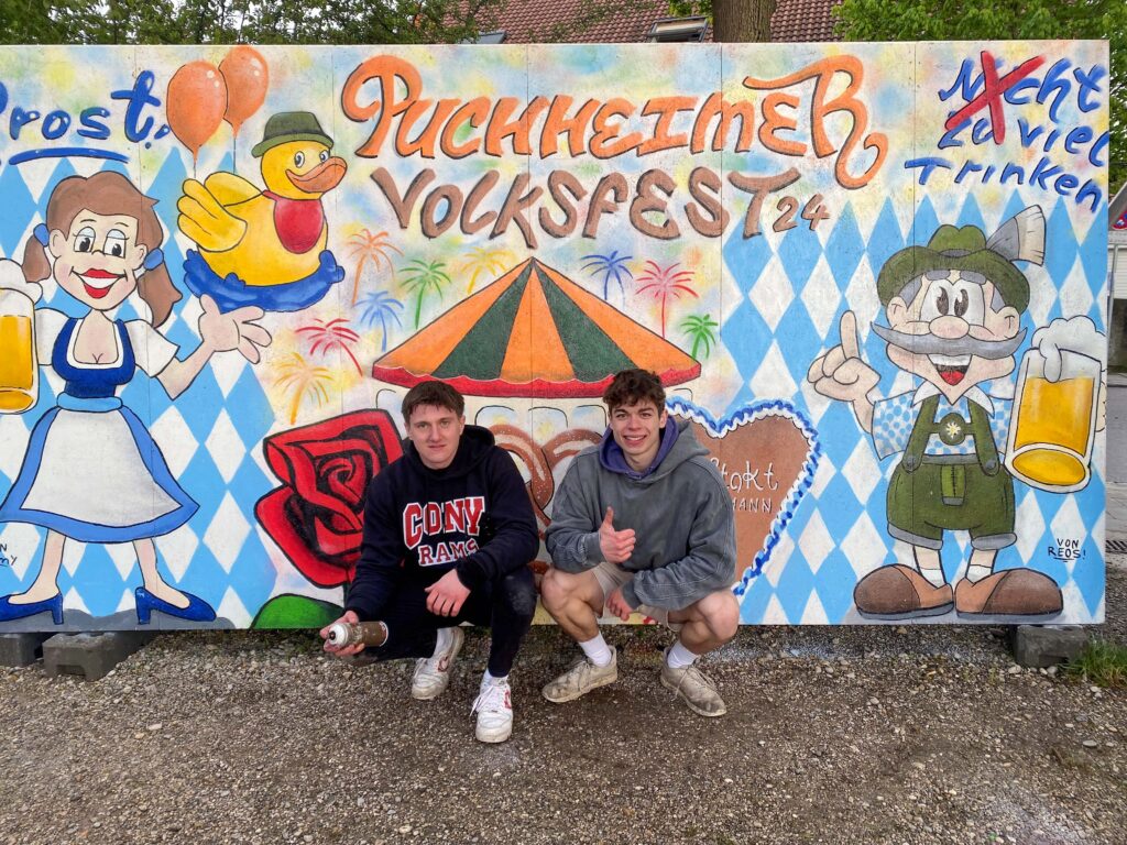 Lennard und Timmy stehen vor ihrem Graffiti-Kunstwerk zum Puchheimer Volksfest 2024